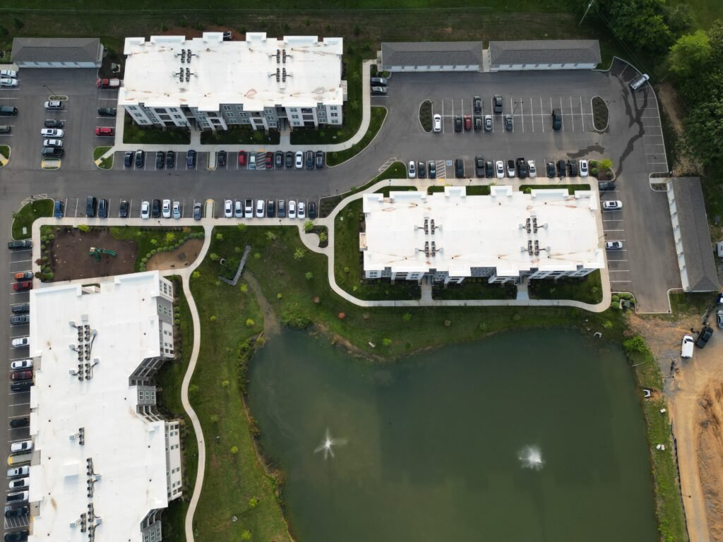 Drone view of apartment buildings, parking lots, and pond in Knoxville, TN.